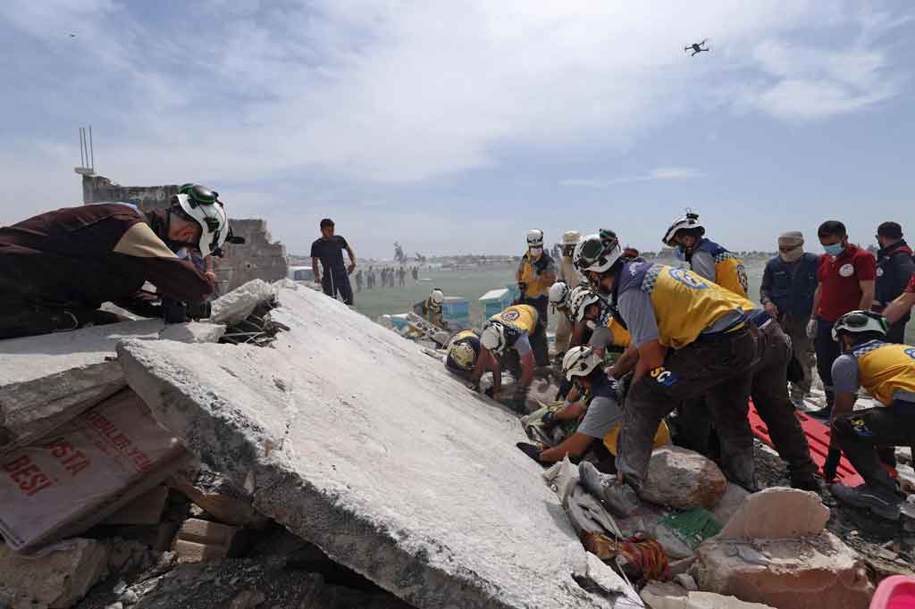 Anggota layanan Pertahanan Sipil Suriah (White Helmets) mencari orang-orang yang terluka di reruntuhan gedung setelah sebuah ledakan terjadi di sebuah depot senjata di dekat kamp pengungsi internal di dekat Kota Fuaa, Idlib, pada Senin, 3 Mei 2021.