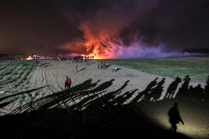 Warga Palestina berkumpul di tengah pembakaran asap ban dan gas air mata yang ditembakkan oleh pasukan keamanan Israel di perbatasan Israel-Gaza, di al-Bureij di Jalur Gaza tengah.