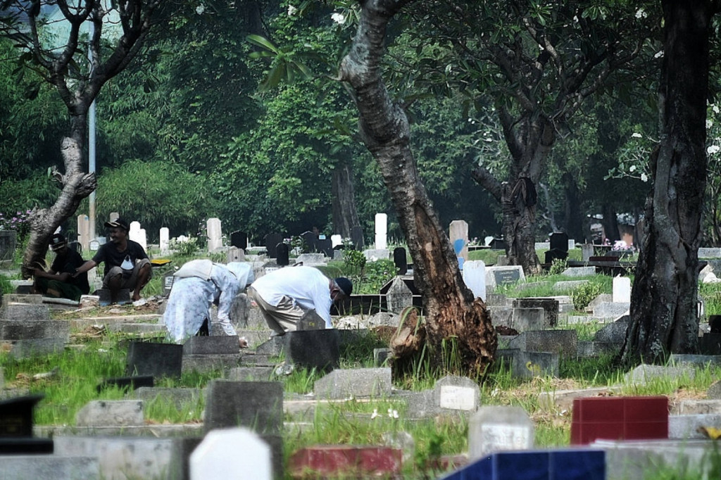 Sejumlah peziarah masih bisa masuk ke TPU Menteng Pulo, Tebet, Jakarta Selatan, meski sudah dilakukan penjagaan. Salah seorang peziarah mengaku diperbolehkan warga sekitar makam sehingga bisa masuk.