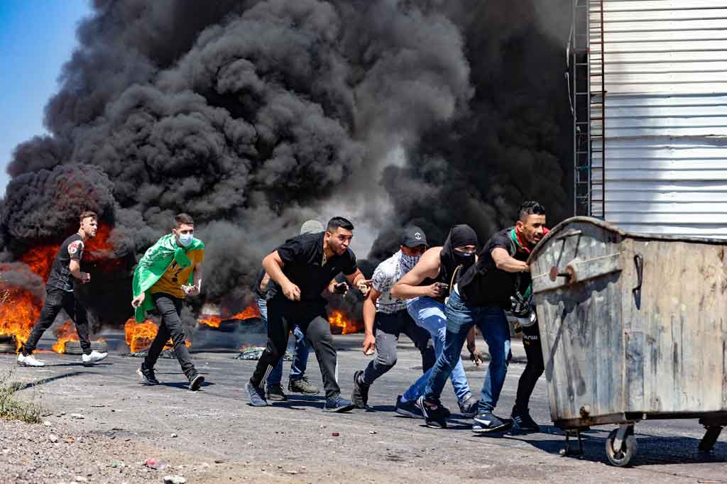 Para pemuda Palestina terlibat bentrokan dengan pasukan keamanan Israel di dekat pos pemeriksaan Hawara, selatan Kota Nablus, Tepi Barat, Jumat, 14 Mei 2021.