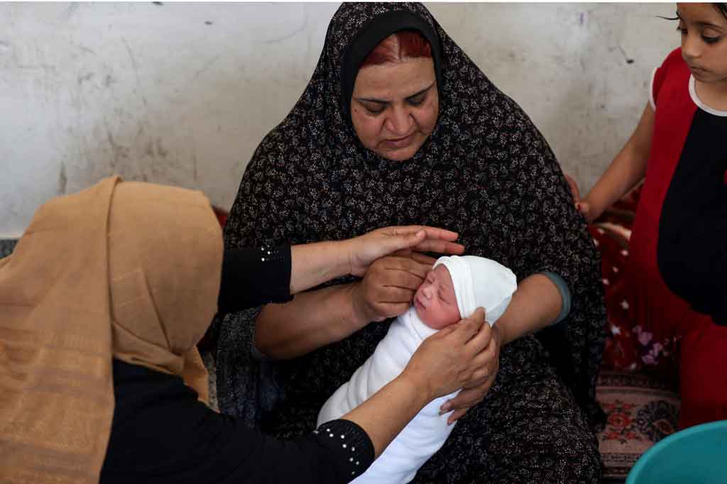 Seorang perempuan Palestina menggendong bayi berusia satu hari yang lahir di sebuah sekolah Perserikatan Bangsa-Bangsa di mana banyak keluarga Palestina yang mengungsi mencari perlindungan di tengah serangan udara dan pemboman oleh pasukan Israel, pada Kamis, 20 Mei 2021.
