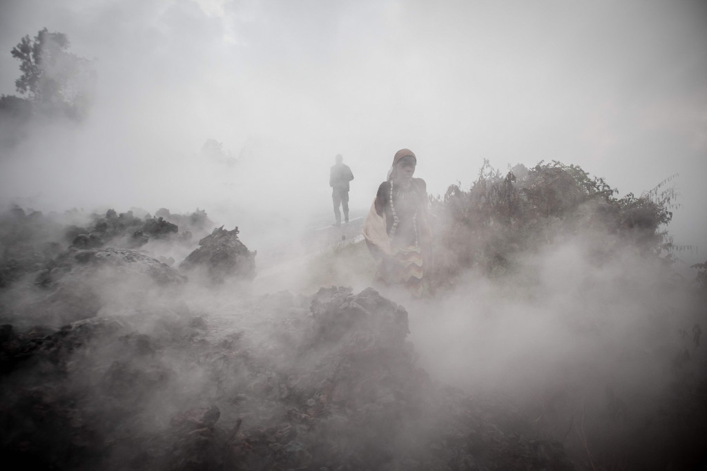 Penduduk berjalan di dekat abu yang membara di pagi hari di Goma di sebelah timur Republik Demokratik Kongo, 23 Mei 2021, setelah letusan Gunung Nyiragongo.