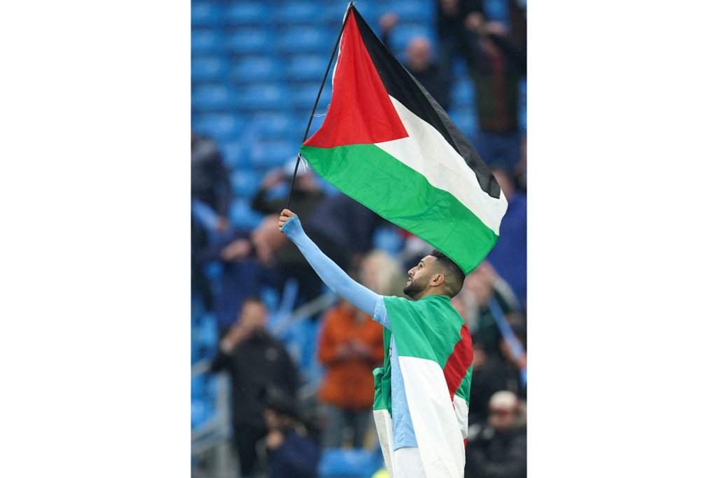 Riyad Mahrez mengibarkan bendera Palestina saat perayaan gelar Liga Inggris, di Stadion Etihad, Minggu, 23 Mei 2021. Hal itu dilakukan Mahrez sebagai bentuk dukungan kepada Palestina di tengah konflik dengan Israel.