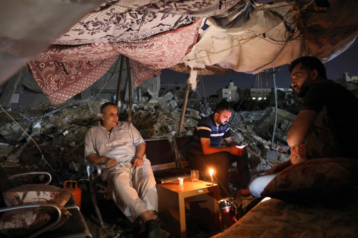 Warga Palestina duduk di tenda yang didirikan di atas reruntuhan bangunan yang hancur dalam serangan udara Israel di Kota Gaza, 24 Mei 2021.