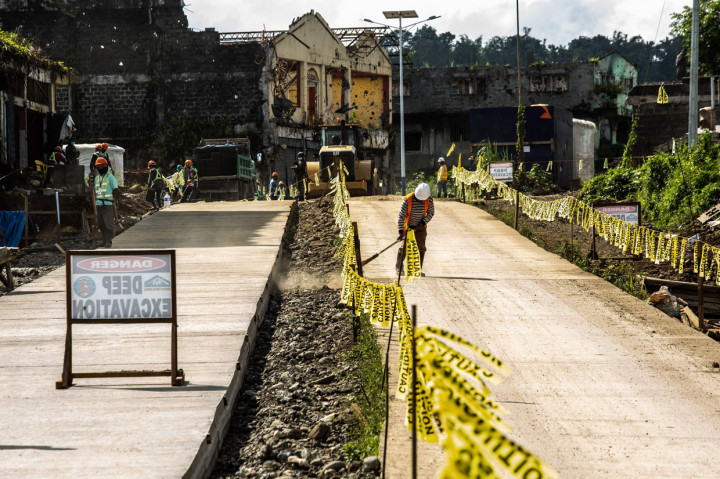 Para pekerja berdiri di sepanjang jalan yang baru diaspal empat tahun setelah militan ISIS mengepung Kota Marawi di Mindanao, Filipina, 23 Mei 2021.
