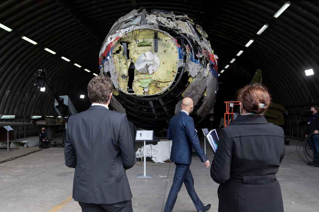 
Para juri memeriksa bagian luar pesawat yang dengan susah payah dirakit kembali, masih dilapisi cat putih, merah dan biru Malaysia Airlines, dan kemudian menaiki tangga untuk melihat ke dalam kerusakan.