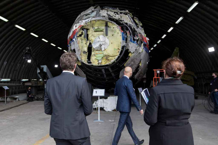 
Para juri memeriksa bagian luar pesawat yang dengan susah payah dirakit kembali, masih dilapisi cat putih, merah dan biru Malaysia Airlines, dan kemudian menaiki tangga untuk melihat ke dalam kerusakan.