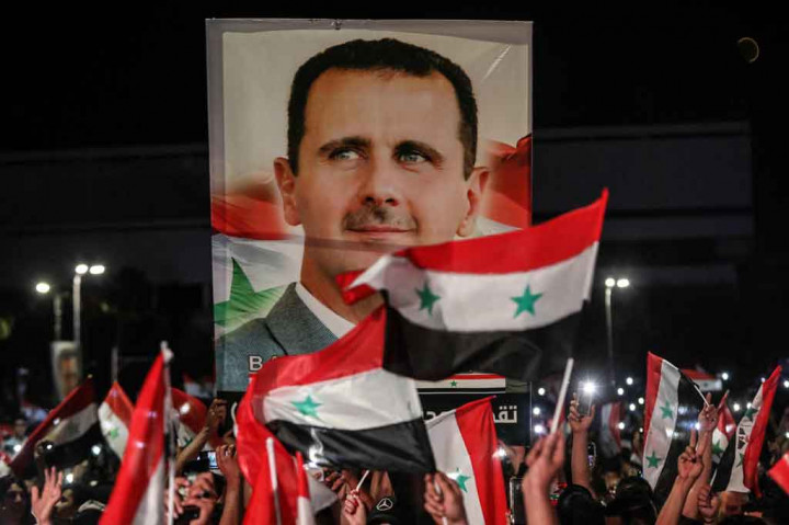 Warga Suriah mengibarkan bendera nasional dan potret besar presiden mereka saat mereka merayakan kemenangan Bashar al-Assad yang terpilih kembali sebagai presiden Suriah pada Kamis, 27 Mei 2021.