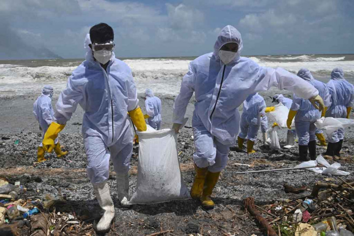 Personel Angkatan Laut dengan pakaian hazmat dikirim untuk membersihkan jutaan butiran plastik yang tercampur dengan minyak yang terbakar dan residu lainnya yang menutupi pantai Negombo, 40 kilometer (25 mil) di utara ibu kota.