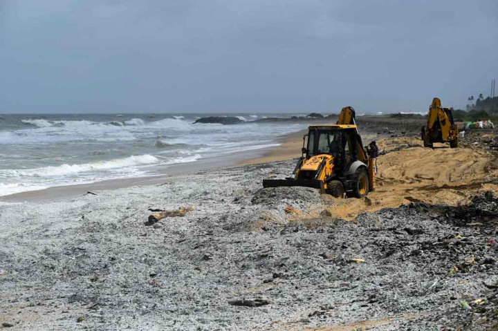 Bulldozer meraup berton-ton pelet plastik yang berasal dari setidaknya delapan kontainer yang jatuh dari kapal pada hari Selasa.