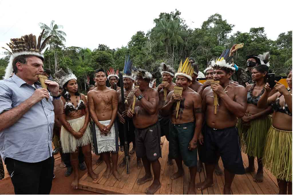 Presiden Brasil Jair Bolsonaro memainkan alat musik tradisional selama perayaan adat peresmian jembatan di Sao Gabriel da Cachoeira, negara bagian Manaus, Brasil, Kamis, 27 Mei 2021.