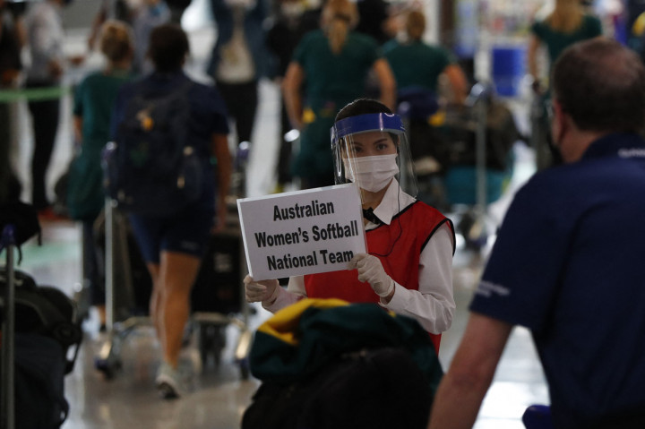 Seorang petugas mengenakan masker dan pelindung wajah menyambut kedatangan pemain timnas softball Australia di Bandara Internasional Narita, Jepang.
