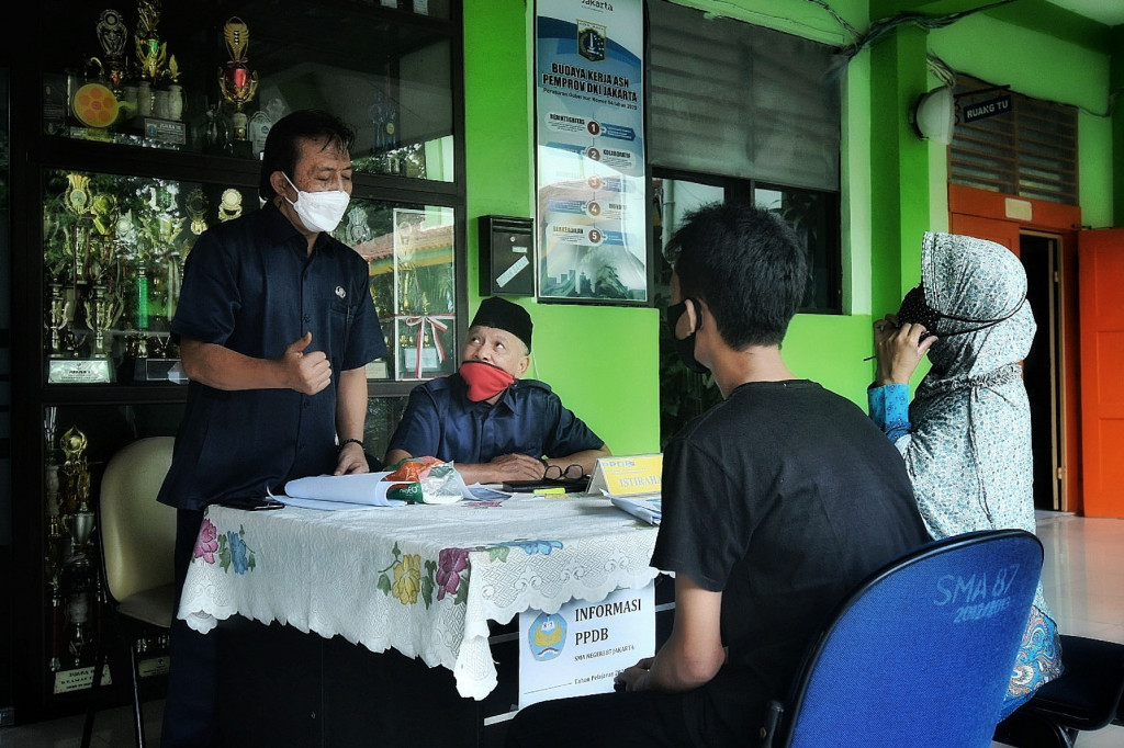 Orang tua murid mencari informasi pengajuan akun untuk mengikuti proses penerimaan Peserta Didik Baru (PPDB) Tahun Pelajaran 2021/2022 di SMA Negeri 87 Jakarta, Senin