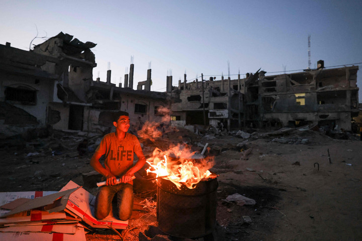 Seorang pemuda Palestina bersiap untuk memasak jagung dekat bangunan yang hancur selama konflik antara Hamas dan Israel pada Mei 2021 di Beit Hanun, Jalur Gaza, Senin, 7 Juni 2021.