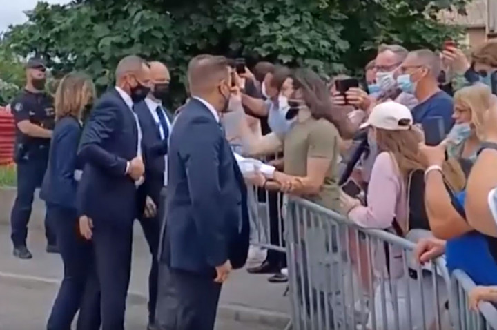 Tanpa diketahui, seorang pria berbaju hijau tiba-tiba melayangkan tangannya ke arah wajah Macron.