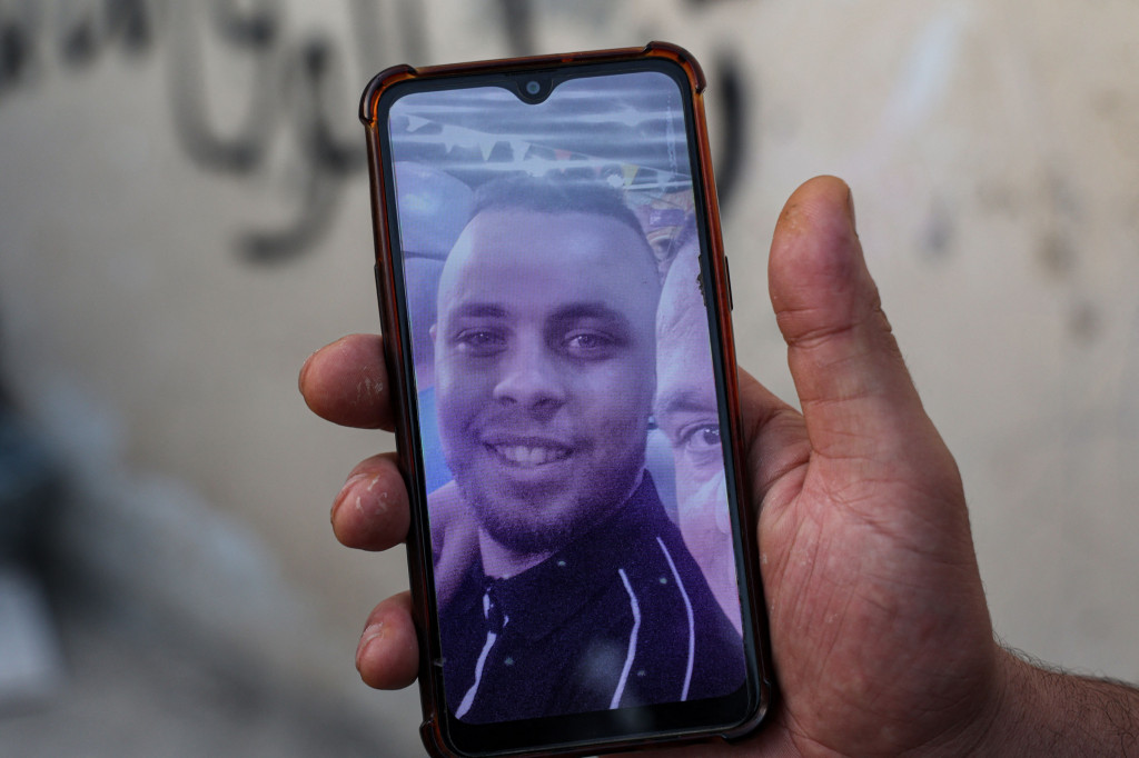 Seorang kerabat Palestina Jamil al-Amuri, yang terbunuh dalam konfrontasi dengan pasukan khusus Israel, memegang telepon yang menunjukkan fotonya di luar sebuah rumah sakit di Jenin di utara Tepi Barat, pada 10 Juni 2021. 
