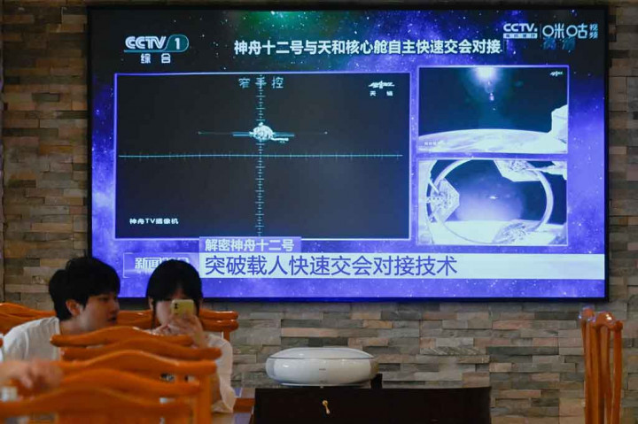 Sebuah TV di sebuah restoran di Beijing pada Jumat, 18 Juni 2021, menyiarkan pesawat ruang angkasa Shenzhou-12 berlabuh dengan stasiun Tiangong.