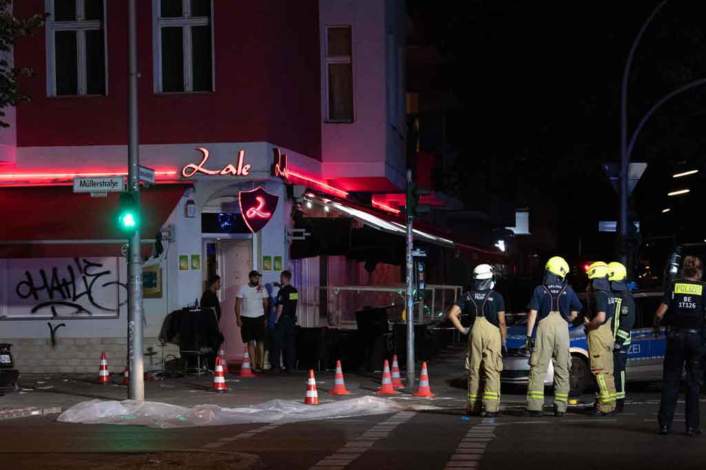 Petugas pemadam kebakaran dan polisi berdiri di TKP di depan bar shisha di Berlin pada Senin, 21 Juni 2021, setelah empat orang terkena tembakan dari mobil yang sedang melaju. 