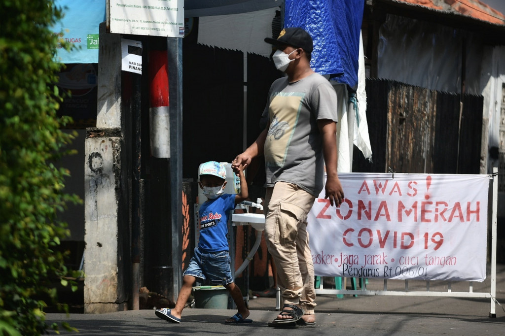 Warga melintas saat penerapan mini lockdown di perkampungan Jalan Madrasah RT 006 RW 001 Gandaria Selatan, Cilandak, Jakarta Selatan.