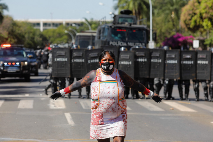 Seorang wanita suku Kayapo menari di depan pasukan polisi selama protes di depan Kongres Nasional di Brasilia, Brasil, Selasa, 22 Juni 2021.