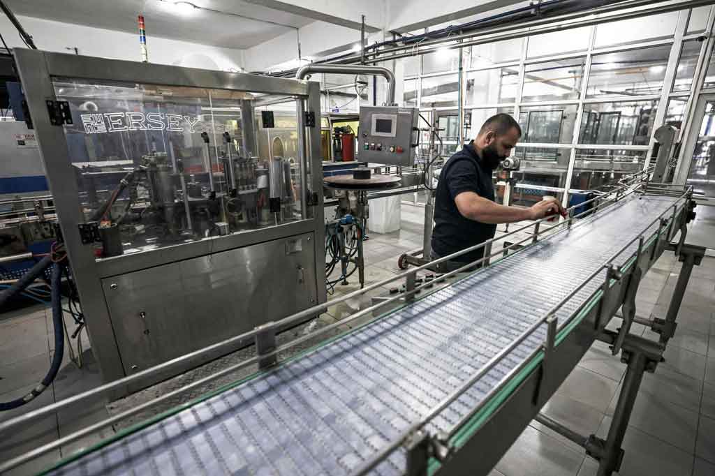 Seorang karyawan Palestina membersihkan jalur produksi yang kosong di pabrik Pepsi di zona industri Gaza pada Senin, 21 Juni 2021.