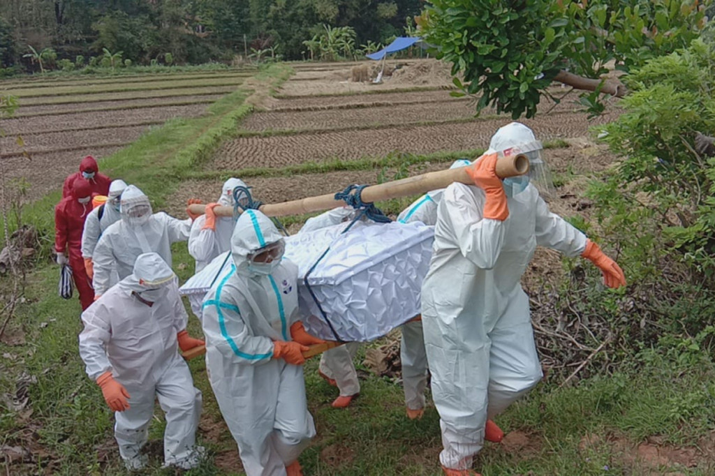 Terlihat jalur yang dilalui menuju permakaman cukup ekstrem. Petugas harus menyeberangi sungai sembari memanggul peti jenazah hingga melewati pematang sawah yang sempit. Tak hanya itu, akses jalan menuju area permakaman juga menanjak.