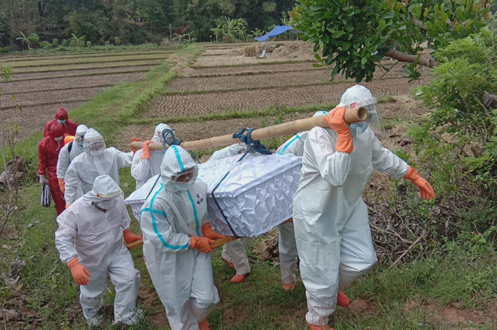 Terlihat jalur yang dilalui menuju permakaman cukup ekstrem. Petugas harus menyeberangi sungai sembari memanggul peti jenazah hingga melewati pematang sawah yang sempit. Tak hanya itu, akses jalan menuju area permakaman juga menanjak.