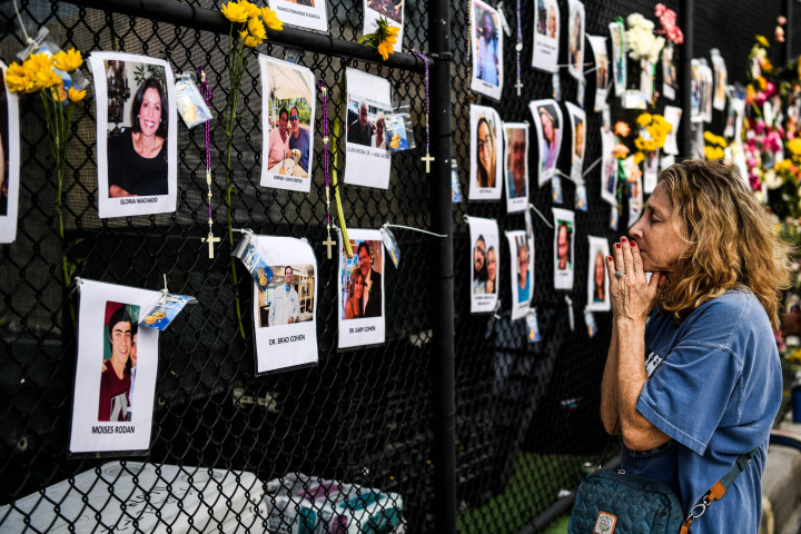 Seorang wanita berdoa di depan foto-foto di peringatan darurat untuk para korban runtuhnya gedung, dekat lokasi kecelakaan di Surfside, Florida, utara Miami Beach pada 27 Juni 2021.
