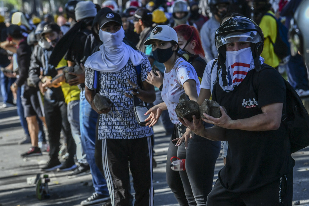 Demonstran membawa batu saat bentrok dengan polisi selama protes terhadap pemerintah di Medellin, Kolombia.