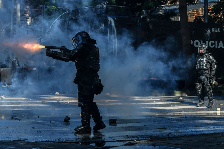 Seorang polisi antihuru-hara menembakkan gas air mata ke arah demonstran selama protes terhadap pemerintah di Medellin, Kolombia.