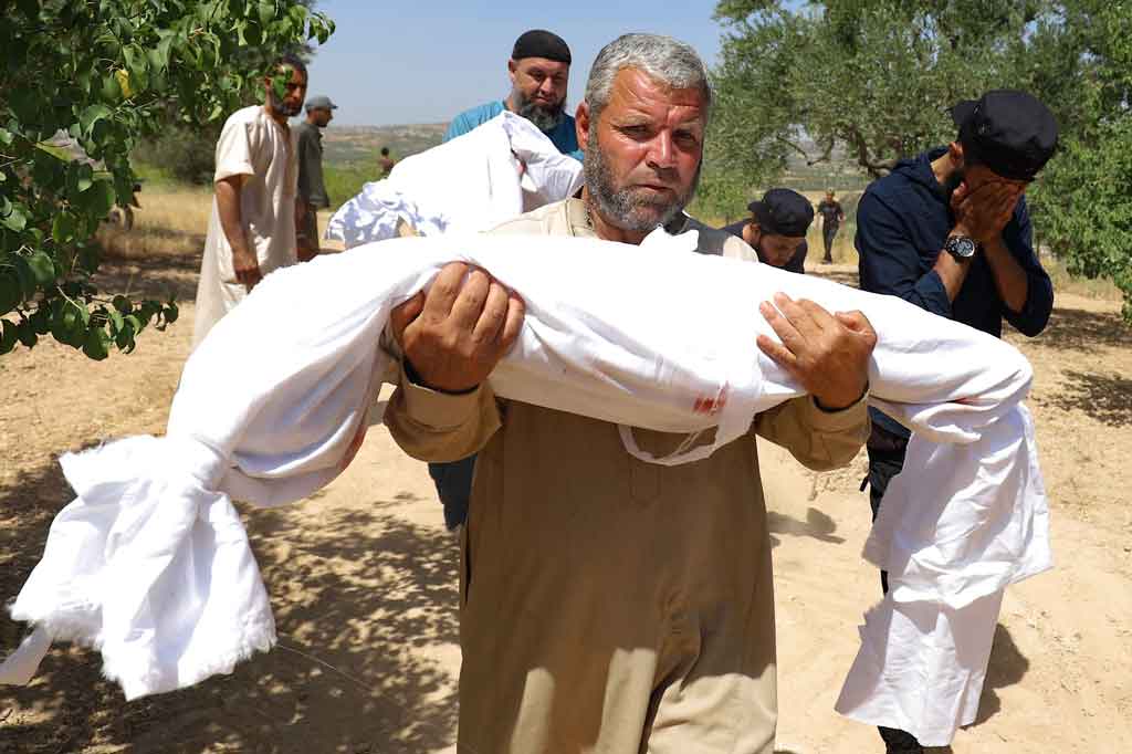 Warga membopong jenazah seorang anak yang menjadi salah satu korban dalam penembakan artileri rezim di Desa Iblin, wilayah Jabal al-Zawiya, Idlib, yang dikuasai pemberontak, pada Sabtu, 3 Juli 2021.