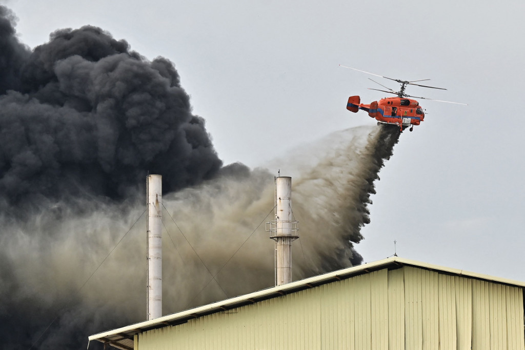 Sebuah helikopter membuang air ke lokasi ledakan dan kebakaran di sebuah pabrik plastik di pinggiran Bangkok pada 5 Juli 2021.
