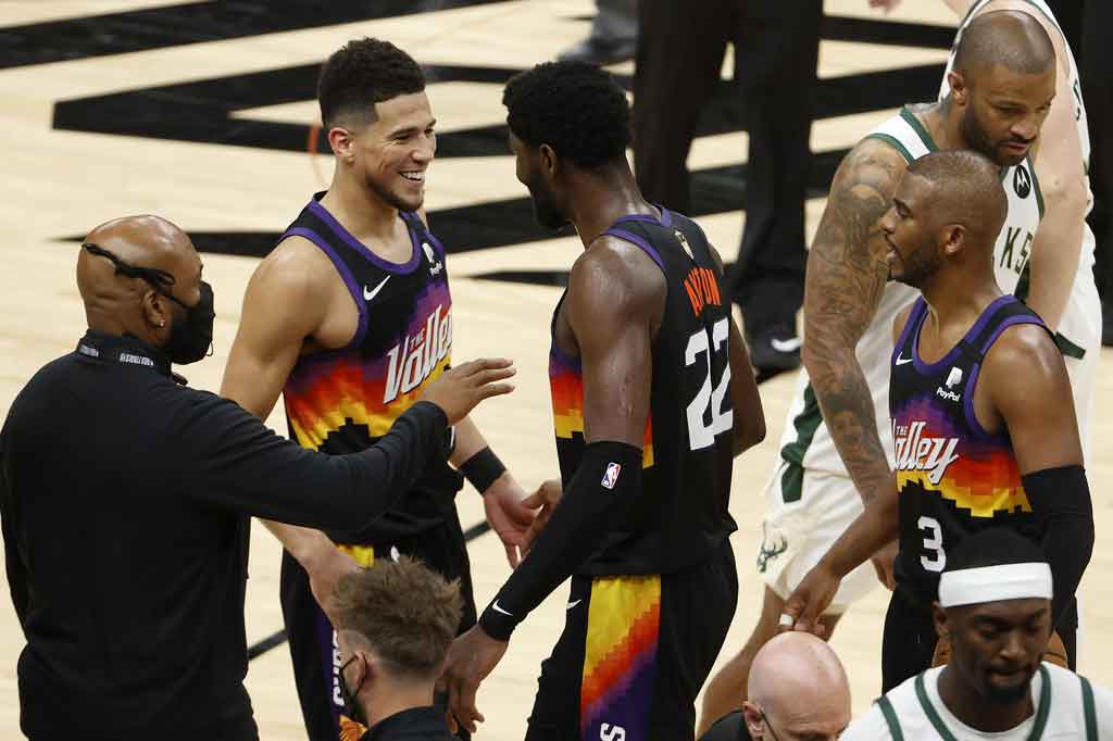 Devin Booker (1), Deandre Ayton (22), dan Chris Paul (3) dari Phoenix Suns merayakan kemenangan melawan Milwaukee Bucks di fim pertama Final NBA di Phoenix Suns Arena, Phoenix, Arizona, Rabu, 7 Juli 2021.