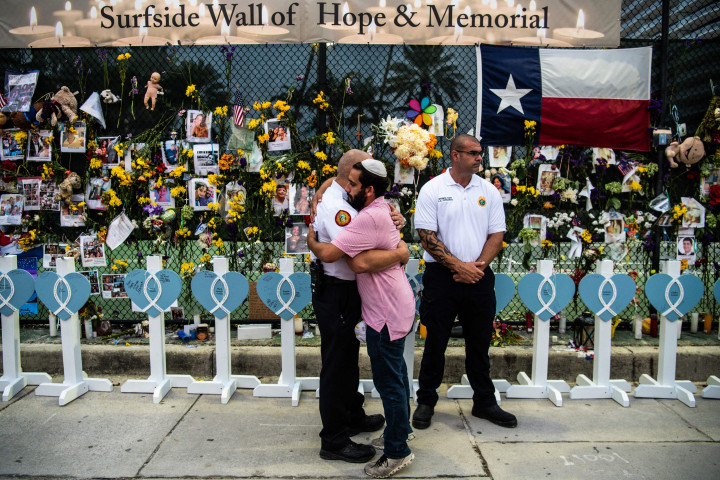 Seorang anggota Pemadam Kebakaran Miami-Dade memeluk kerabat korban di