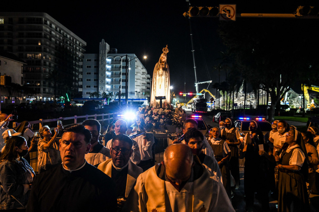 Orang-orang dari Gereja Katolik St. Joseph membawa patung keagamaan di dekat lokasi bangunan yang runtuh di Surfside, Florida, utara Miami Beach, pada 7 Juli 2021.