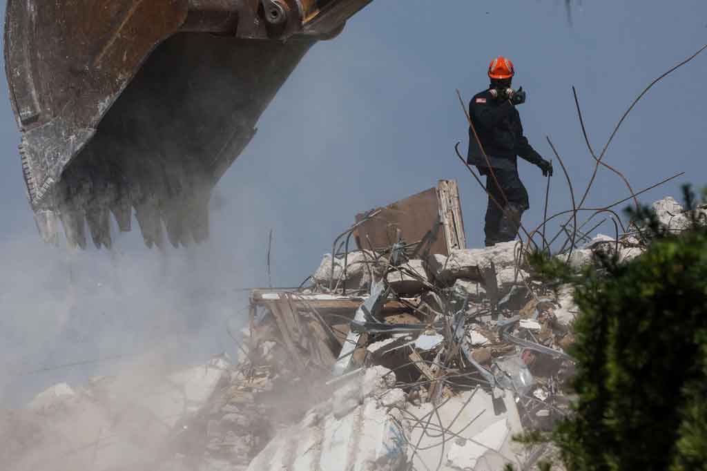 Seorang pekerja penyelamat memandu ekskavator untuk menggali sisa-sisa bangunan kondominium Champlain Towers South 12 lantai yang runtuh di Surfside, Florida pada Jumat, 9 Juli 2021 waktu setempat.