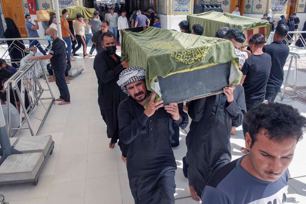 Warga Irak membawa peti mati kerabat yang meninggal dalam kebakaran besar yang melanda bangsal isolasi virus korona di rumah sakit Al-Hussein di kota Nasiriyah, Irak selatan, selama prosesi pemakaman di pusat kota Najaf, pada 13 Juli 2021.