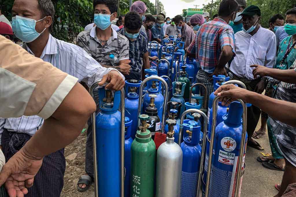 Ratusan orang mengantre melintasi Yangon saat matahari terbit pada Rabu, 14 Juli 2021, dengan harapan dapat mengisi ulang tabung oksigen biru untuk dibawa pulang untuk anggota keluarga mereka yang terkena virus korona.