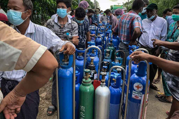 Ratusan orang mengantre melintasi Yangon saat matahari terbit pada Rabu, 14 Juli 2021, dengan harapan dapat mengisi ulang tabung oksigen biru untuk dibawa pulang untuk anggota keluarga mereka yang terkena virus korona.