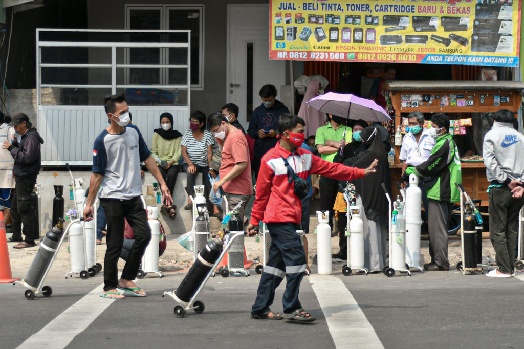 Warga membawa tabung oksigen usai melakukan pengisian ulang oksigen medis yang dibagikan secara gratis di kawasan Manggarai, Jakarta.
