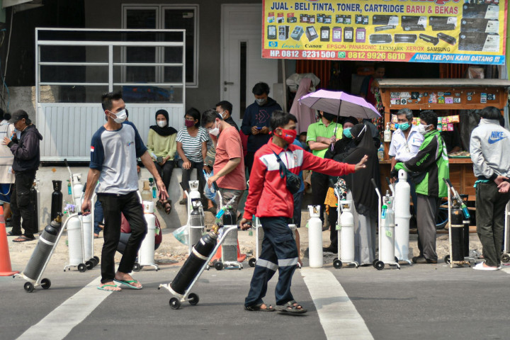 Warga membawa tabung oksigen usai melakukan pengisian ulang oksigen medis yang dibagikan secara gratis di kawasan Manggarai, Jakarta.