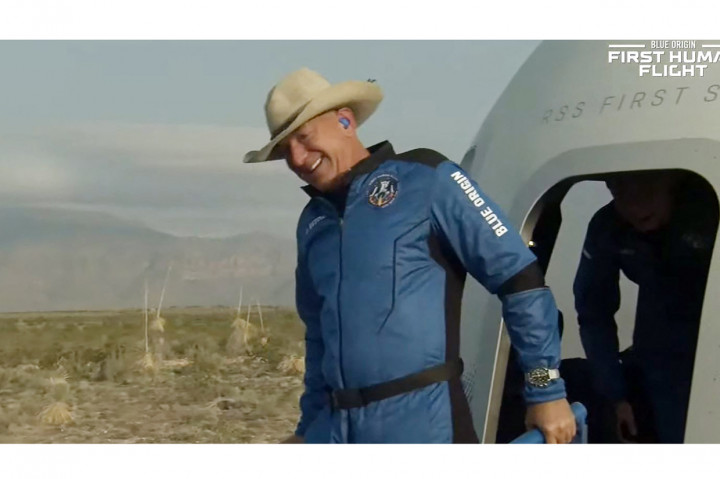 Bezos keluar sambil menggunakan topi koboi.
