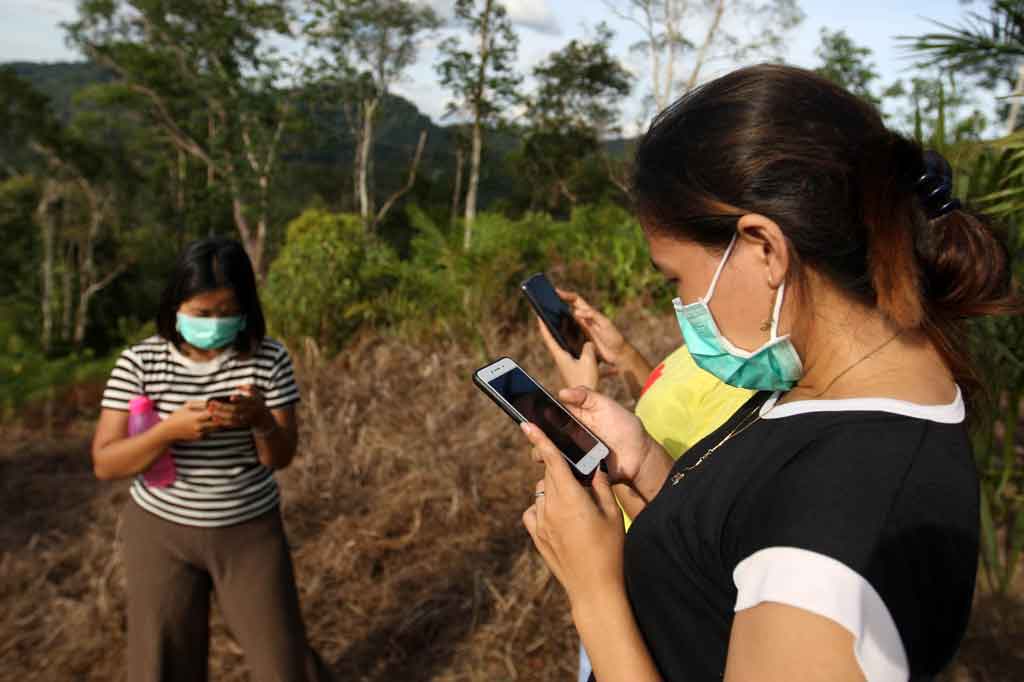 Warga tengah menjelajah internet menggunakan gawai di atas bukit sinyal di Desa Tebuah Elok, Kecamatan Subah, Kabupaten Sambas, Kalimantan Barat. 