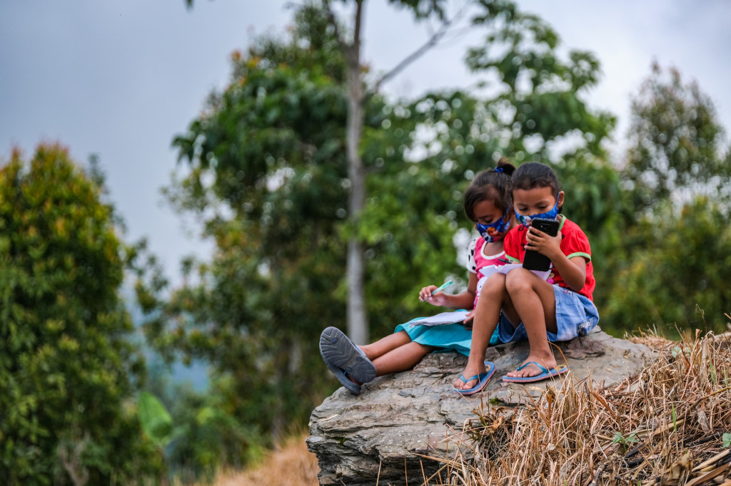 Kristin Frederika (kiri) dan Mumut Kartika siswi kelas 1 SD Inpres Matantimali belajar jarak jauh menggunakan gawai di sebuah bukit yang mampu menangkap sinyal internet di Desa Matantimali, Marawola Barat, Kabupaten Sigi, Sulawesi Tengah.