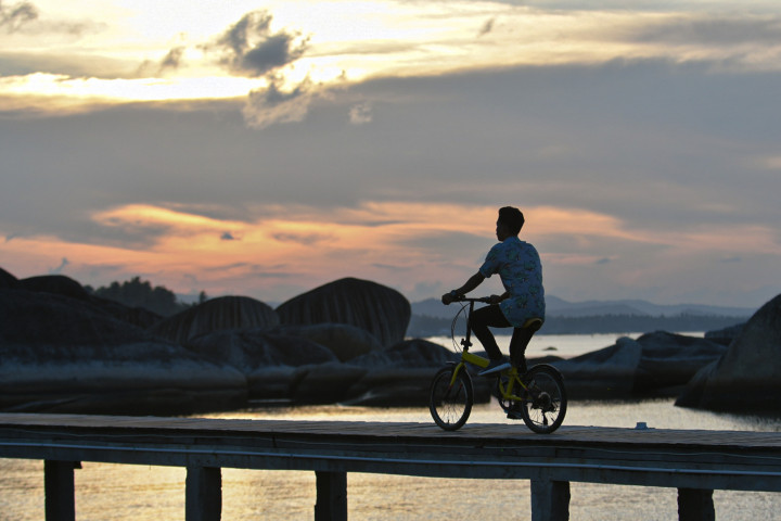 Warga bersepeda saat berwisata di kawasan Pantai Tapak Natuna, Natuna, Kepulauan Riau.