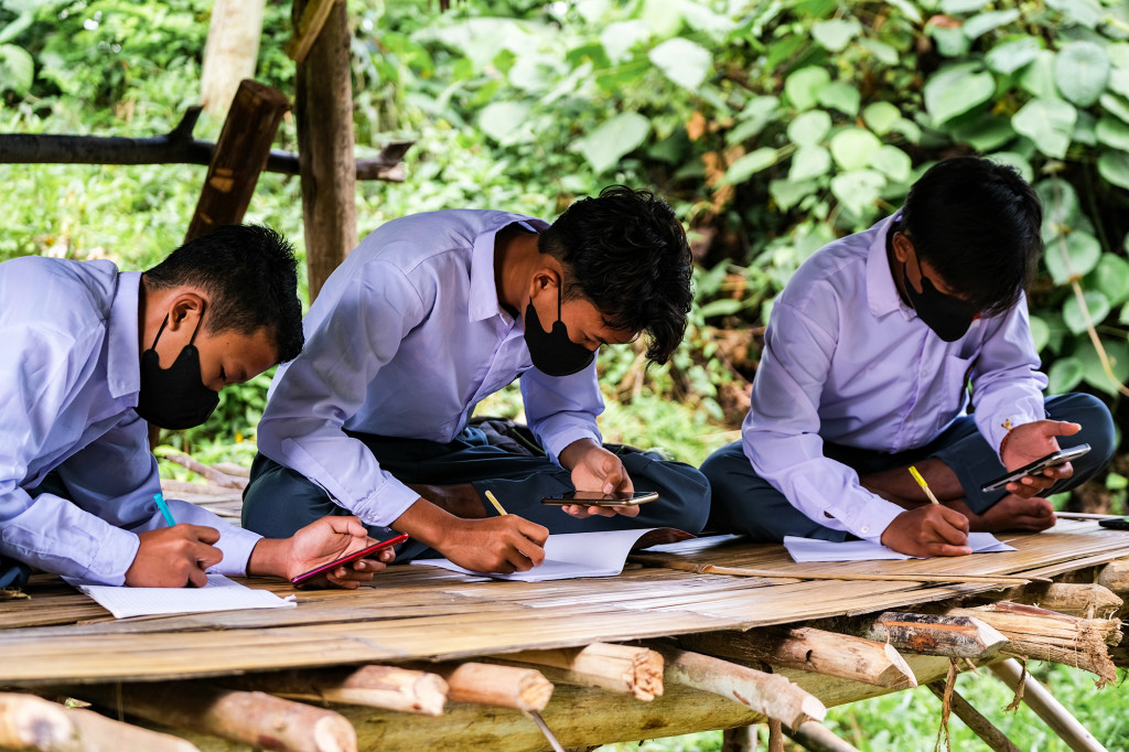 (Dari kiri) Ahmad Hanafi, Rifki Kurniawan, dan Iksan Saputra, pelajar kelas XI MAN 1 Donggala, belajar jarak jauh menggunakan gawai mereka di salah satu spot sinyal internet yang berada di gubuk Desa Tanampulu, Banawa Selatan, Donggala, Sulawesi Tengah (Sulteng).