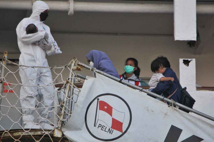 Seorang petugas kesehatan membantu menggendong bayi saat satu keluarga menaiki Kapal Motor Umsini yang diubah menjadi lokasi isolasi pasien covid-19, di Pelabuhan Soekarno-Hatta, Makassar, Sulawesi Selatan pada Senin, 2 Agustus 2021.