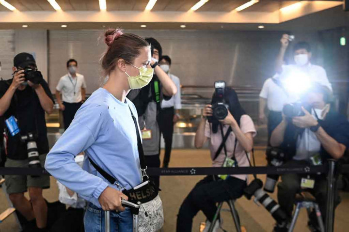 Dikawal oleh pejabat, Tsimanouskaya, yang mengenakan masker kuning dan kacamata hitam, tiba di Bandara Narita Rabu pagi setelah meninggalkan Kedutaan Polandia di Tokyo. Dia naik penerbangan menuju Wina, Austria.