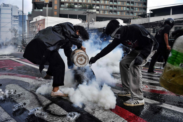 Para pengunjuk rasa pro-demokrasi mengeluarkan tabung gas air mata ketika mereka bentrok dengan polisi selama demonstrasi menuntut reformasi politik dan menyerukan perubahan pada program vaksinasi virus korona negara itu di Bangkok pada 7 Agustus 2021.