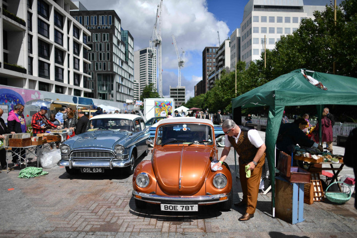Pedagang memoles kap mesin WW Beatle di Classic Car Boot Sale, London.